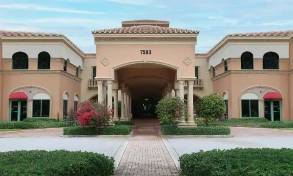 Internal medicine doctor office with arched stucco entrance, terracotta roof, and landscaped walkway